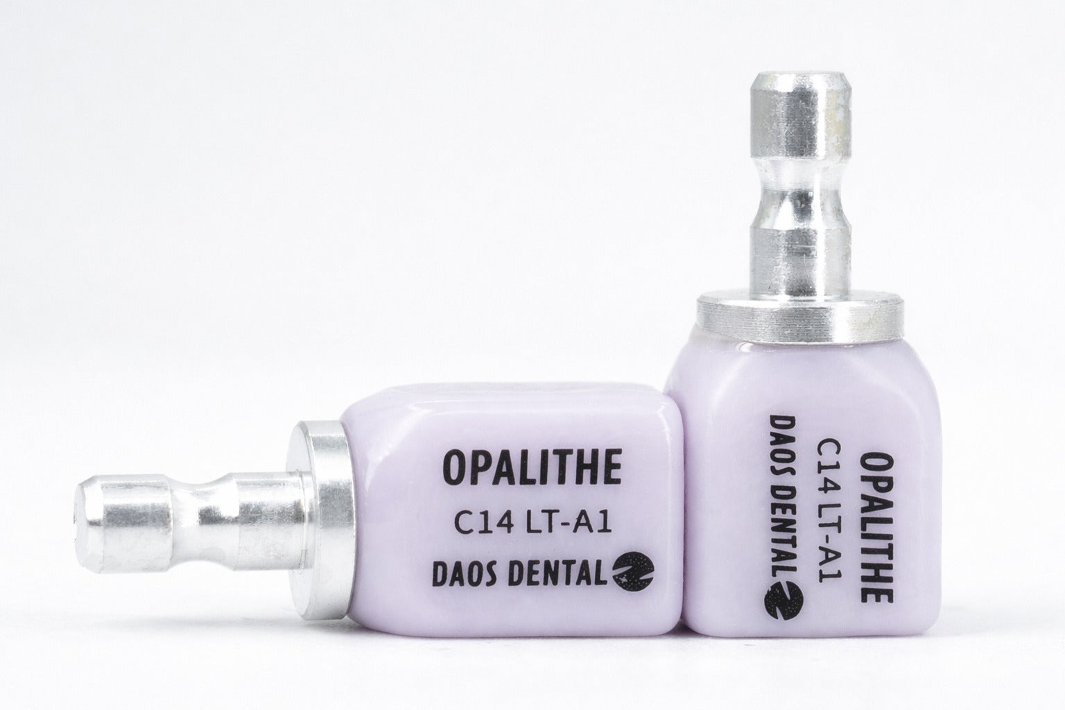 Deux blocs en disilicate de lithium d'apparence violette pour fraisage dentaire, de marque DAOS DENTAL, modèle CAMEX C14 LT-A1, avec insert métallique. 